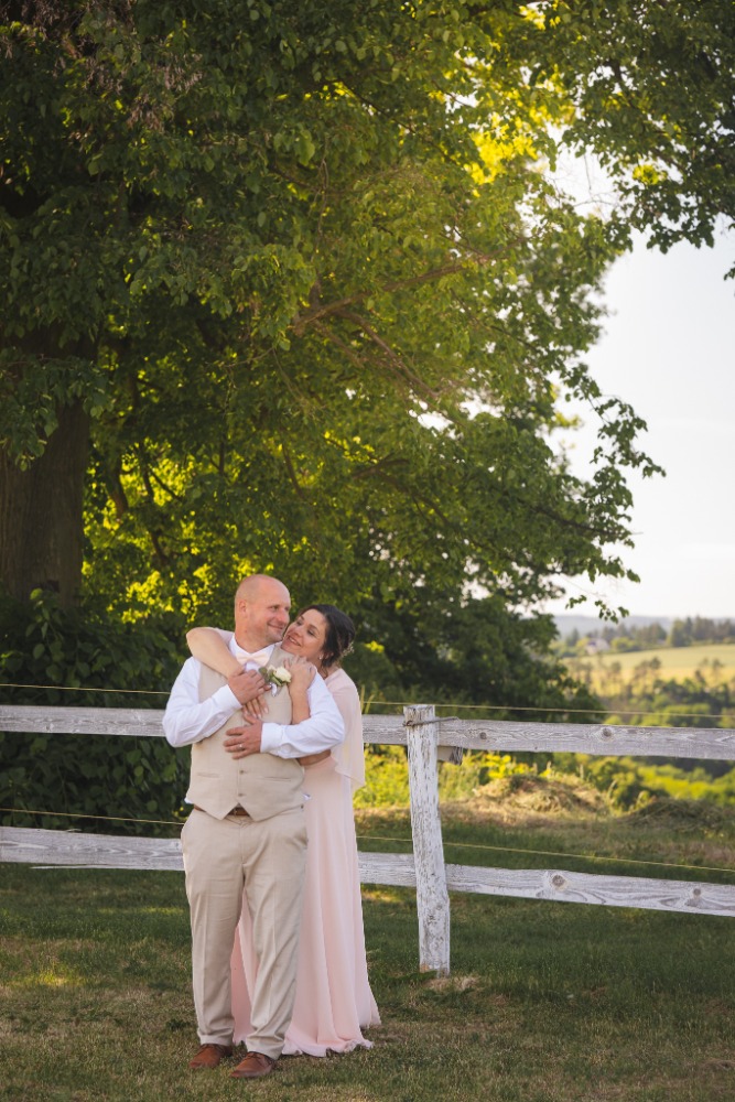 Objetí u bílého plotu s výhledem na zelené kopce